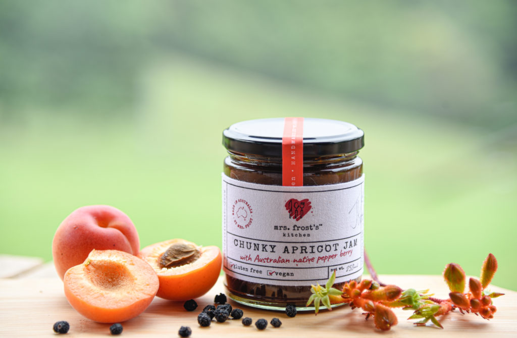 A jar of chunky apricot jam showing key ingredients of apricots and native pepper berries