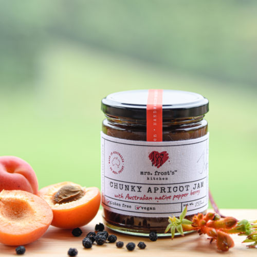 A jar of chunky apricot jam showing key ingredients of apricots and native pepper berries