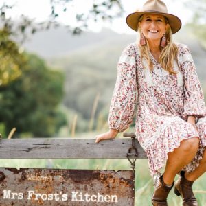 Julie Frost sitting on the farm gate
